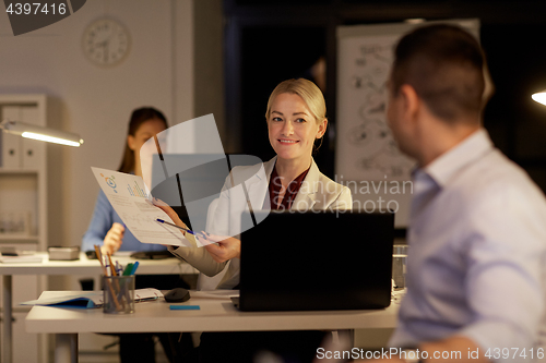 Image of coworkers with papers working late at night office