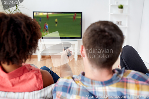 Image of friends watching soccer game on tv at home