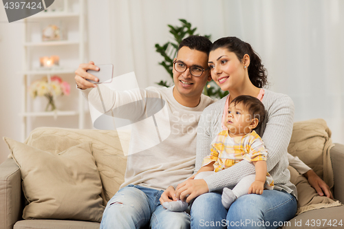 Image of mother and father with baby taking selfie at home