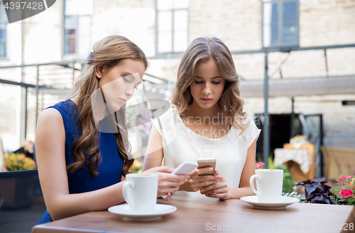 Image of young women with smartphones and coffee at cafe