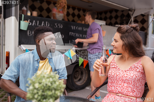Image of friends with drinks sitting at table at food truck