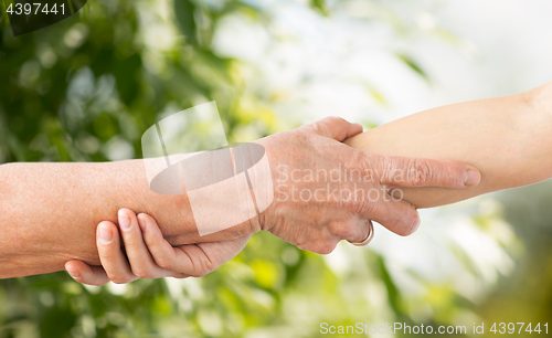 Image of close up of senior and young woman holding hands