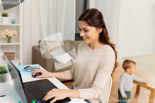 Image of happy mother with baby and laptop working at home