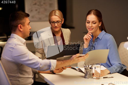 Image of business team with papers working late at office