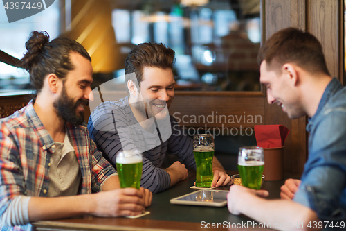 Image of friends with tablet pc and green beer at pub