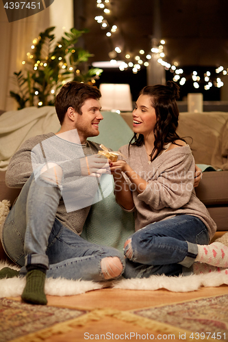 Image of happy couple with gift box at home