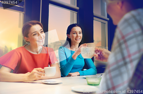 Image of happy young women drinking tea or coffee at cafe