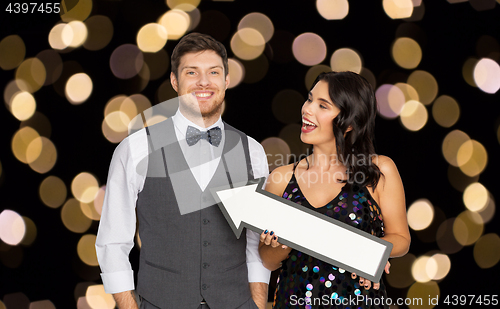 Image of happy couple with big arrow at party