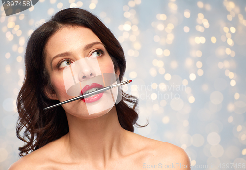 Image of beautiful woman holding make up brush for lipstick