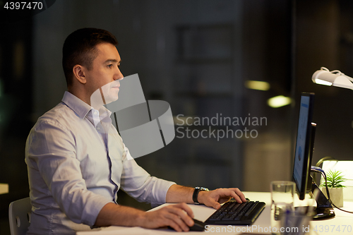 Image of businessman with computer working at night office