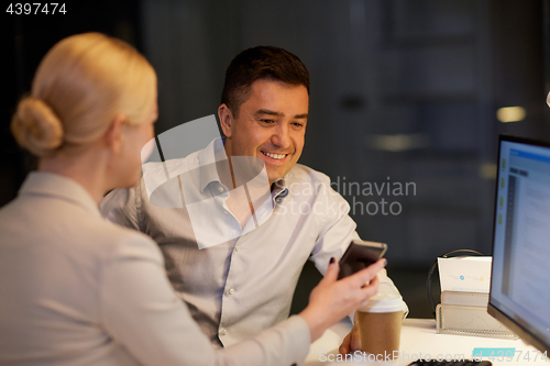 Image of business people with smartphone at night office