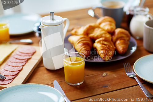 Image of coffeepot and glass of juice on table at breakfast