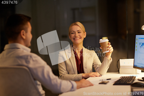 Image of business people drinking coffee at night office