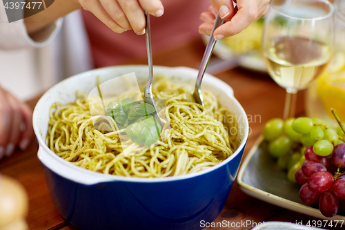 Image of pasta with basil in bowl and other food on table
