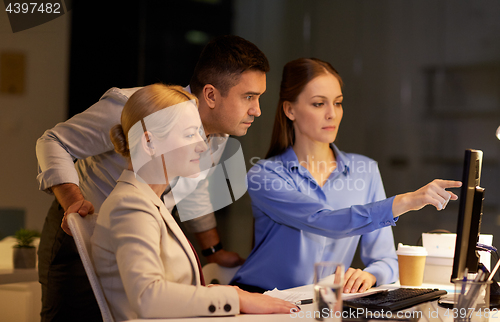 Image of business team with computer working late at office