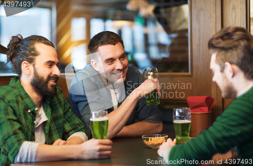 Image of male friends drinking green beer at bar or pub