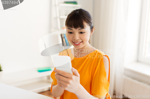 Image of happy asian woman with smartphone at home