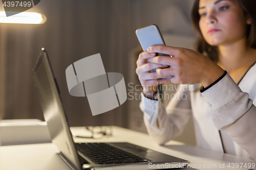 Image of businesswoman with smartphone and laptop at office