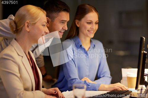 Image of business team with computer working late at office