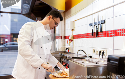 Image of chef making shawarma wrap with meat at kebab shop