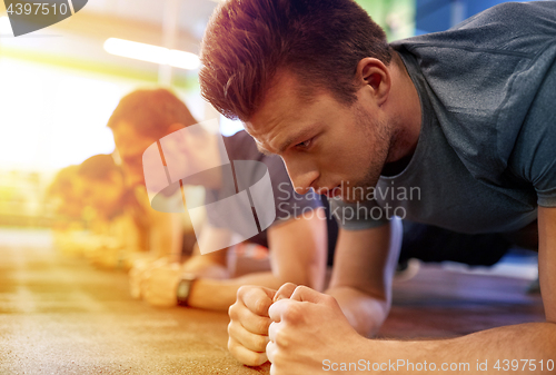 Image of man doing plank exercise at group training in gym