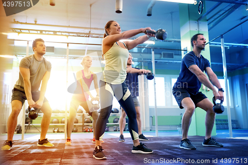 Image of group of people with kettlebells exercising in gym