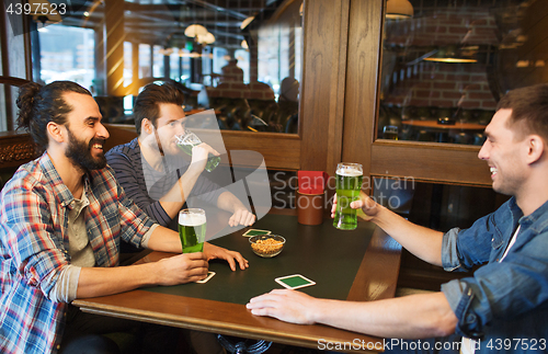 Image of male friends drinking green beer at bar or pub