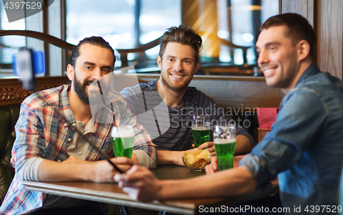 Image of friends taking selfie with green beer at pub