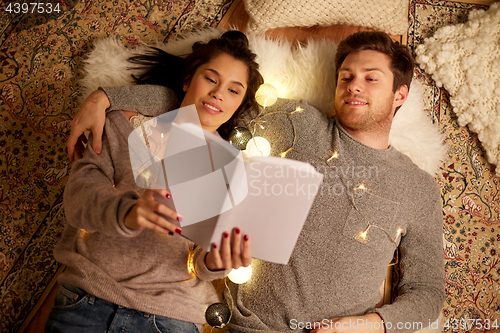 Image of happy couple reading book at home