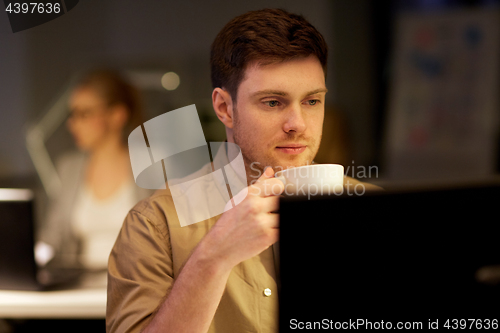 Image of man with laptop and coffee working at night office