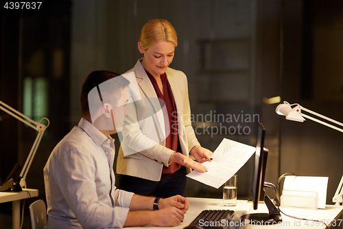 Image of business team with papers working late at office