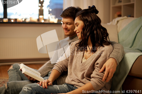 Image of happy couple reading book at home