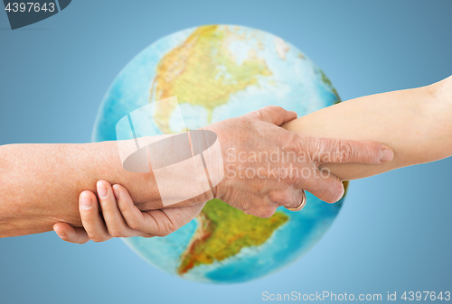 Image of close up of senior and young woman holding hands