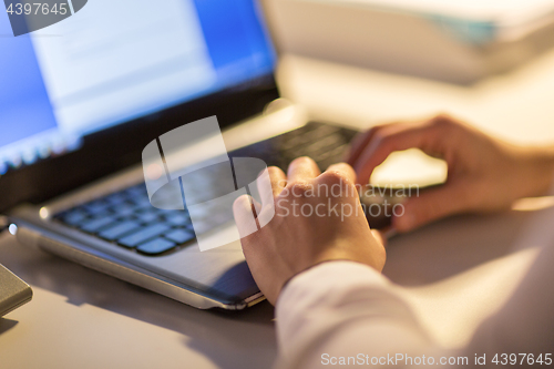 Image of businesswoman with laptop working at night office