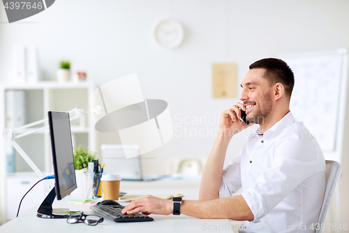 Image of happy businessman calling on smartphone at office