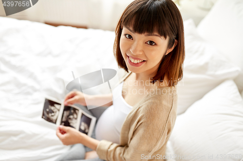 Image of pregnant woman with fetal ultrasound image at home