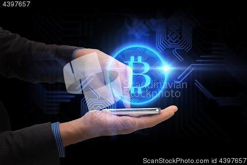 Image of close up of hands with smartphone and bitcoin