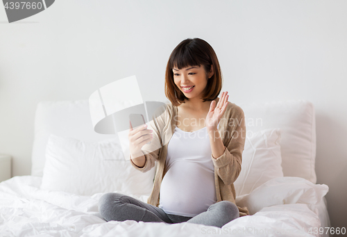 Image of pregnant woman taking selfie by smartphone at home
