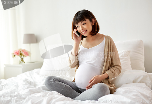 Image of happy pregnant woman calling on smartphone at home