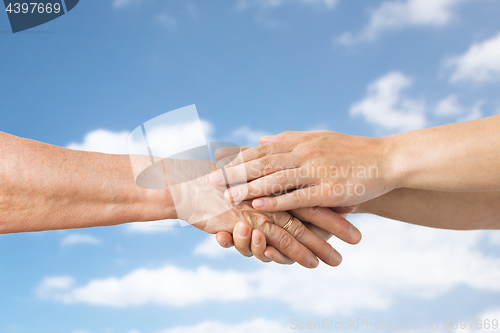 Image of close up of senior and young woman holding hands