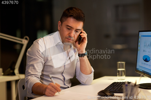 Image of businessman calling on sartphone at night office