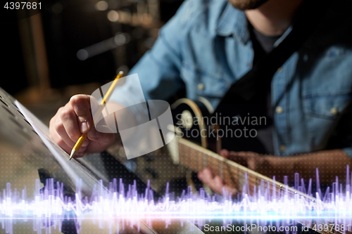 Image of musician with guitar and music book at studio