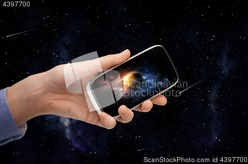 Image of hand with planet on smartphone screen over space