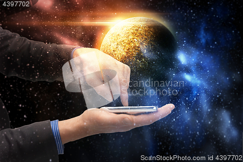 Image of hands holding smartphone over planet in space