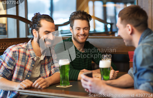 Image of friends with smartphone drinking green beer at pub