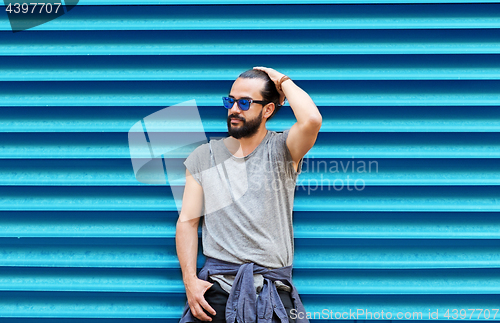 Image of man in sunglasses posing over ribbed blue wall