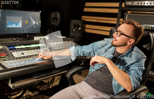 Image of man at mixing console in music recording studio