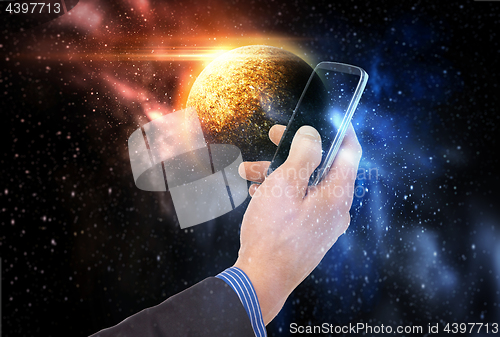 Image of hand holding smartphone over planet in space