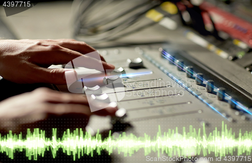 Image of hands on mixing console in music recording studio