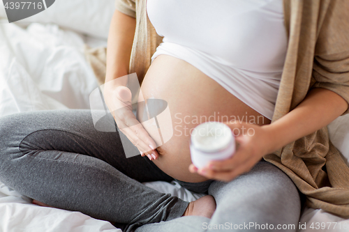 Image of close up of pregnant woman applying cream to belly